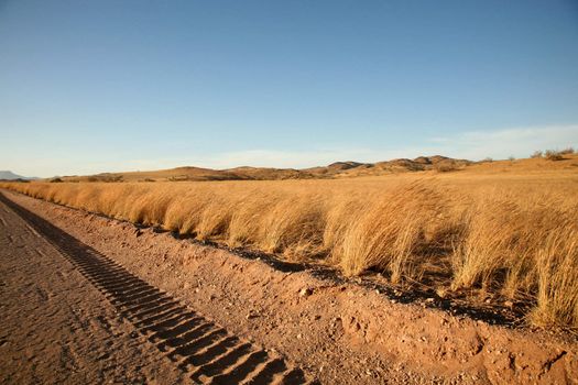 Tire tracks on a gravel road in Namibia with a blue sky