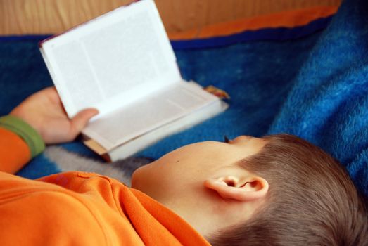 boy lying on bed reading a book at home indoor