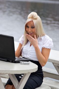 A beautiful young blonde woman is shocked by what she is seeing on her laptop screen.  It looks as if she is possibly seeing something offensive.