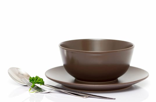 Plate, bowl, spoon and fork with parsley isolated on white (with empty space)
