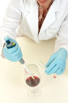 A crime scene investigator or food technologist takes a sample using a pipette for further investigation and analysis.  Focus to pipette tip and glass.