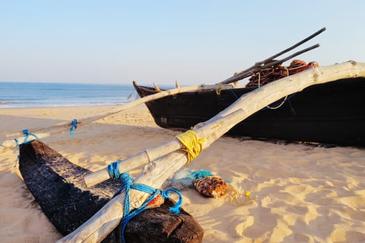 Old boat with fishing net on sandy shore. In Goa