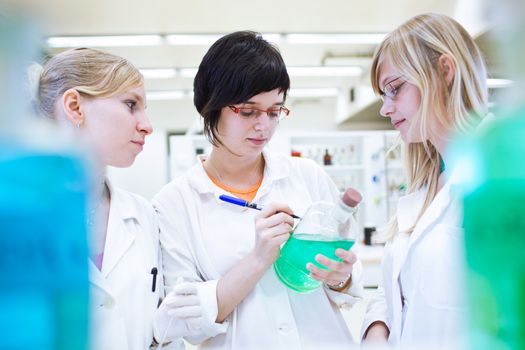 three researchers/chemistry students carrying out research in a chemistry lab (color toned image; shallow DOF)