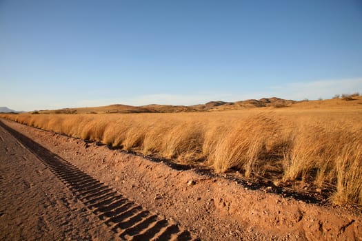 Tire tracks on a gravel road in Namibia with a blue sky