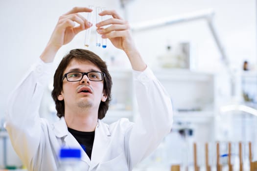 young, male researcher/chemistry student carrying out scientific research in a lab (shallow DOF; color toned image)