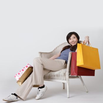 Shopping woman of Asian sit on chair and holding bags with smiling.