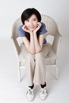 Asian beauty sitting on chair with adorable expression.