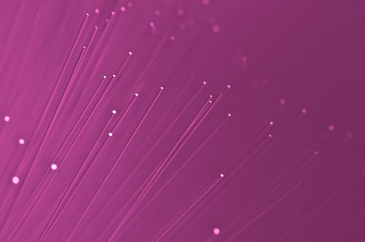 Many ends of vibrant pink illuminated fiber optic light strands close up