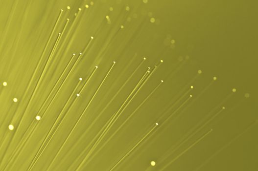 Many ends of yellow illuminated fiber optic light strands close up