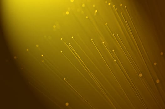 Many ends of yellow illuminated fiber optic light strands close up. Golden light effect.