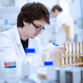 young, male researcher/chemistry student carrying out scientific research in a lab (shallow DOF; color toned image)