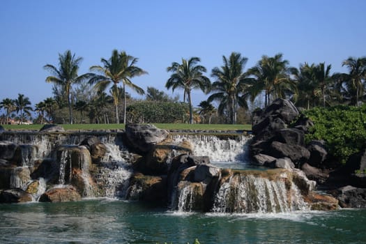 sceneic rocky waterfalls with palms in background