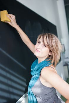 pretty college student erasing the chalkboard/blackboard during a math class (color toned image; shallow DOF)