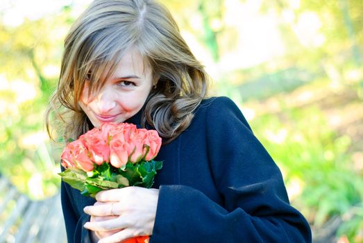 Beautiful young woman with a bouquet of red roses