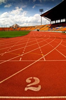 Running track number in front of tracks and stadium with blue sky and white cloud.