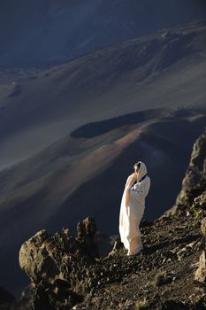 The girl at craters of Haleakala. Early morning, a smoke, wrapped up in white the girl in rising sun beams costs at edge of breakage against craters.