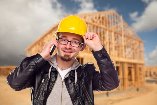 Young Contractor Wearing Hard Hat on Cell Phone In Front of Construction Site.