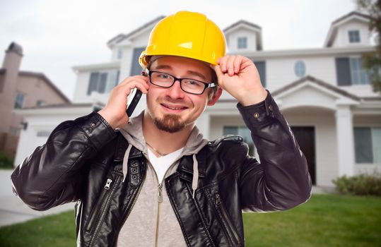 Young Contractor Wearing Hard Hat on Cell Phone In Front of House.