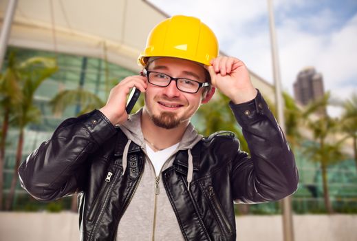 Smiling Young Cunstruction Worker Talking on Cell Phone In Front of Building.