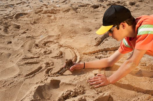 Creative teenager sketching a cartoon on beach sand