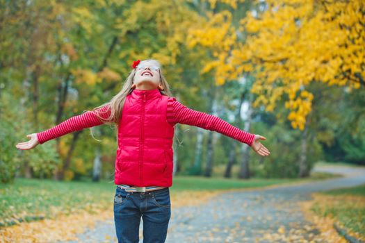 Cute girl walking in the autumn park. Rain, yellow leaves, tree.