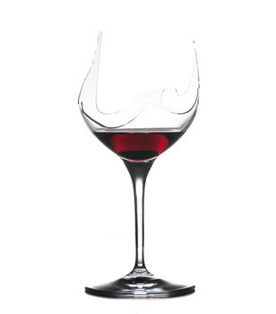Red wine in a broken wine glass isolated against white