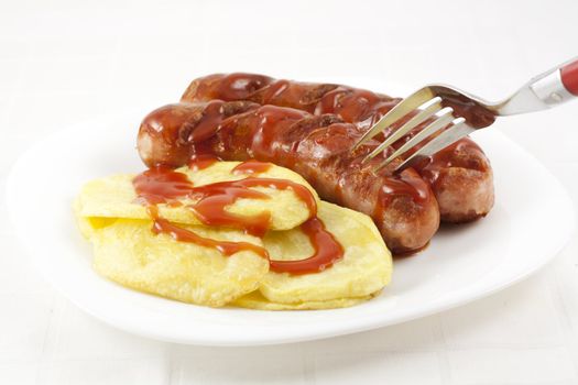 Eating sausages and fried potatoes with ketchup