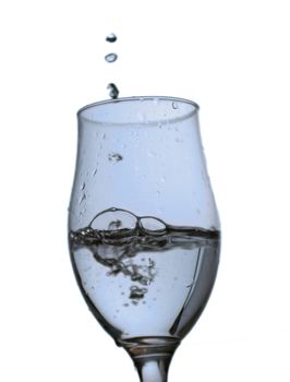 A glass with water pouring from above