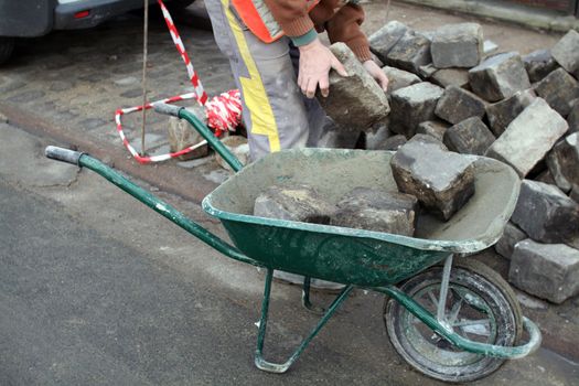 a man transports stones in a wheelbarrow, for repair the pavement