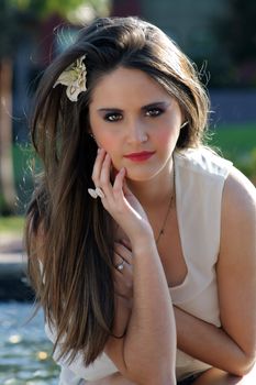 Close-up of a lovely young woman outdoors, backlit by the sun, looking directly at the camera.