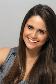 A studio close-up of a lovely young brunette with long, luscious hair and a captivating smile.