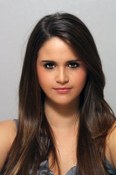 A studio close-up of a lovely young brunette with long, luscious hair and a neutral facial expression.