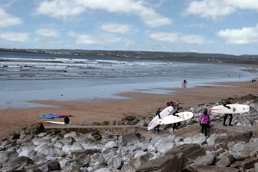 surfers leaving the beach in lahinch county clare ireland on a beautiful day