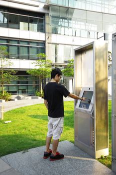 asia boy play the touch screen in modern building outside 