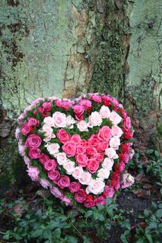 a heart shaped sympathy flower arrangement near a tree