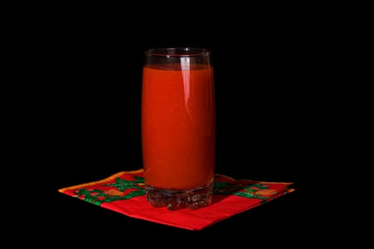 Glass of tomato juice on a black background