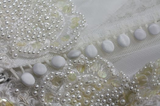 Detail of a white bridal gown or wedding dress with pearls and white buttons