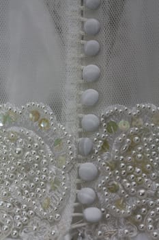 Detail of a white bridal gown or wedding dress with pearls and white buttons