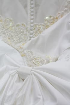 Detail of a white bridal gown or wedding dress with pearls and white buttons