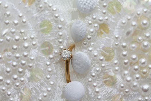 A yellow golden diamond ring on a wedding dress