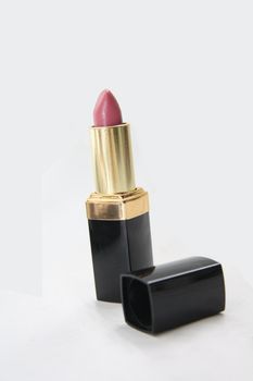 a pink lipstick in a black and golden package