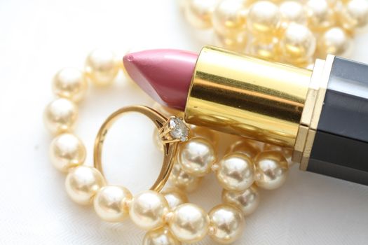 A pink lipstick, diamond engagement ring and pearl necklace, accessories of a bride on her wedding day