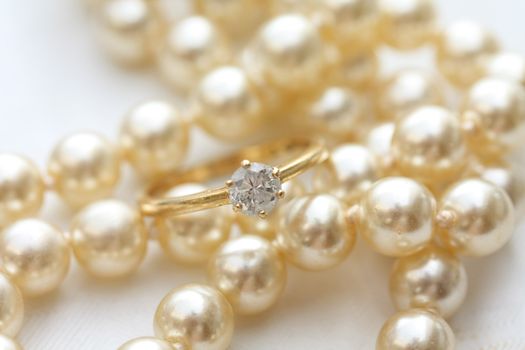 A solitaire diamond engagment ring on a pearl necklace