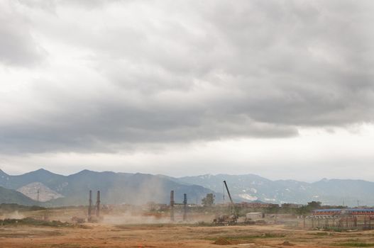 Dust flies with construction in developing Asia with mountains in the background