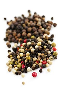 Mixed assorted peppercorns on white background macro