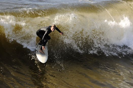 Surfer gets up on a wave. The wave twists with foam and splashes.