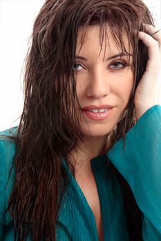 Beautiful woman with brunette semi wavy wet tousled hair and blue eyes is staring into the camera.