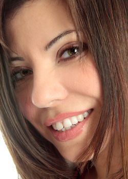 A closely cropped face of a beautiful brunette woman smiling and looking at camera.