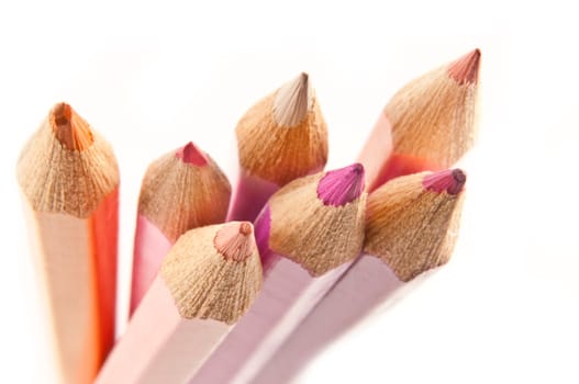 Close up of the ends of a group of pastel coloured artist pencils arranged over white