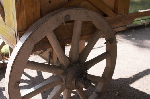 High resolution image. A wooden old vintage cart wheel alongside a barn.